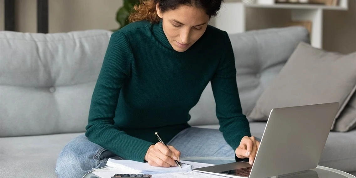 Woman interacting with laptop and filling out forms on a couch