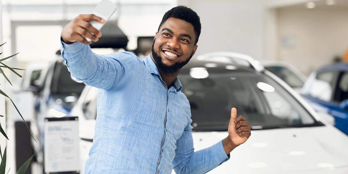 Happy Man Making Selfie Near Automobile Gesturing Thumbs-Up In Dealership