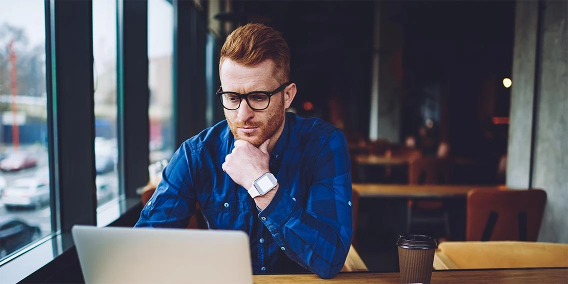 man in coffee shop looking at laptop