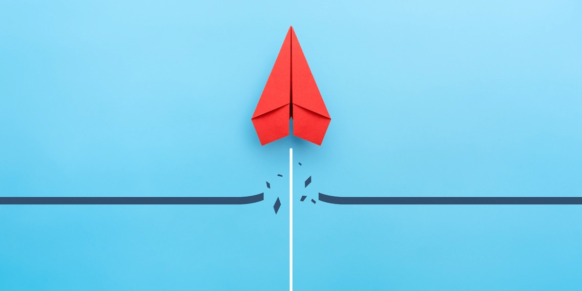 Red paper airplane crossing a blue line