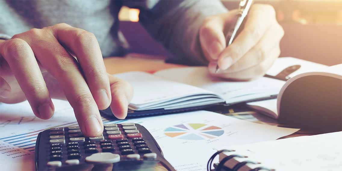a person holding a pen in his hand and writing something