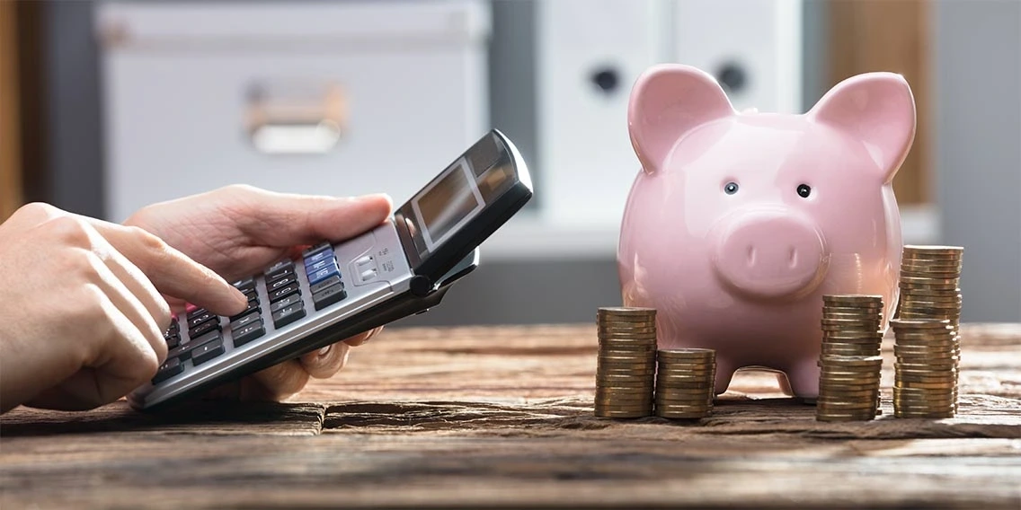 calculator and piggy bank with stacked pennies