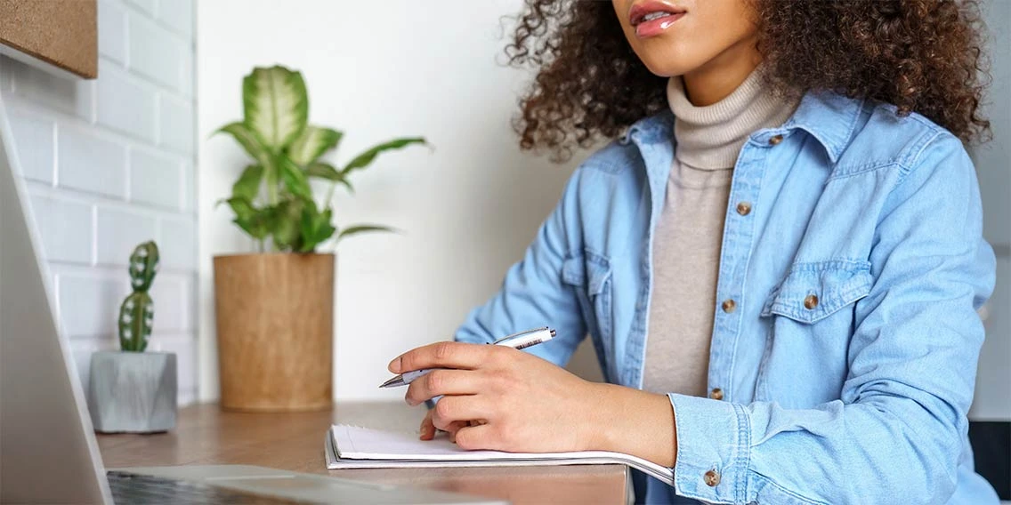 a girl sitting on a desk with a papaer and pen