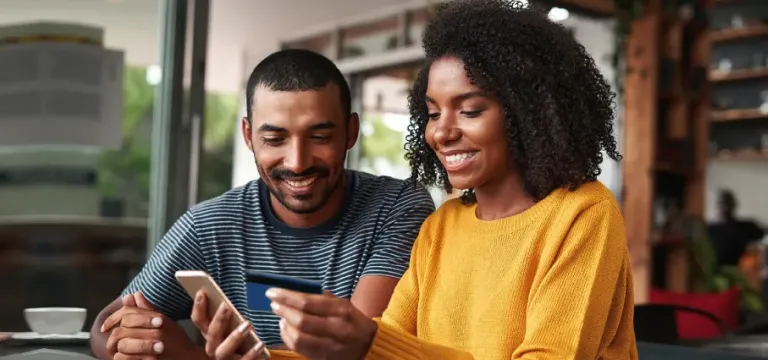 couple sitting together and holding a card and phone