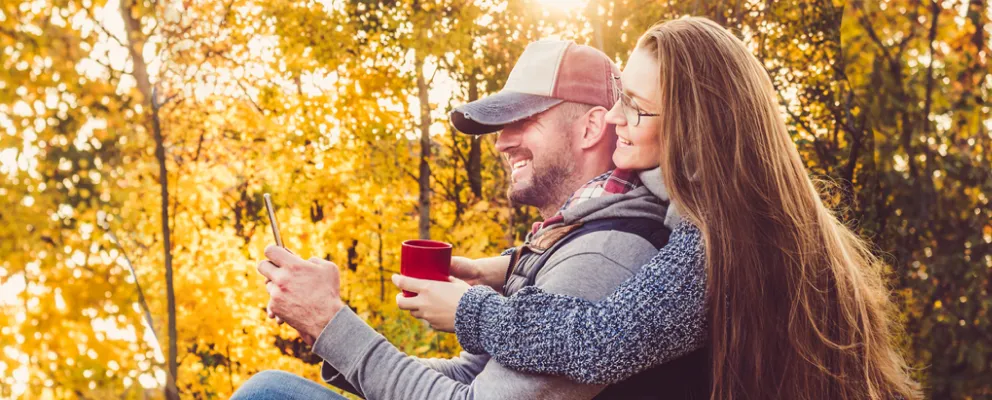 Couple sitting in the autumn outdoor viewing their mobile phone