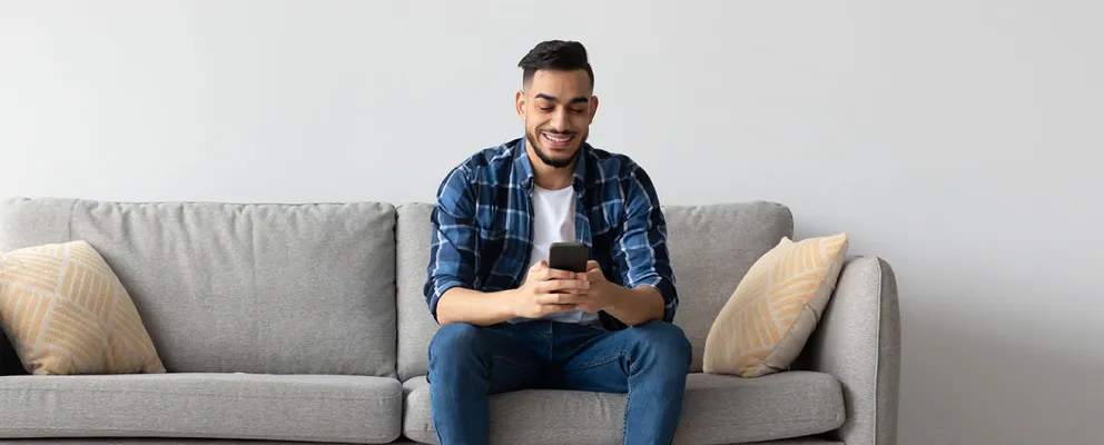 man sitting on a sofa and looking at the phone