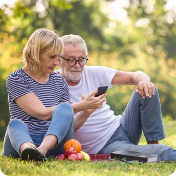 senior couple relaxing in the park while viewing their mobile phone