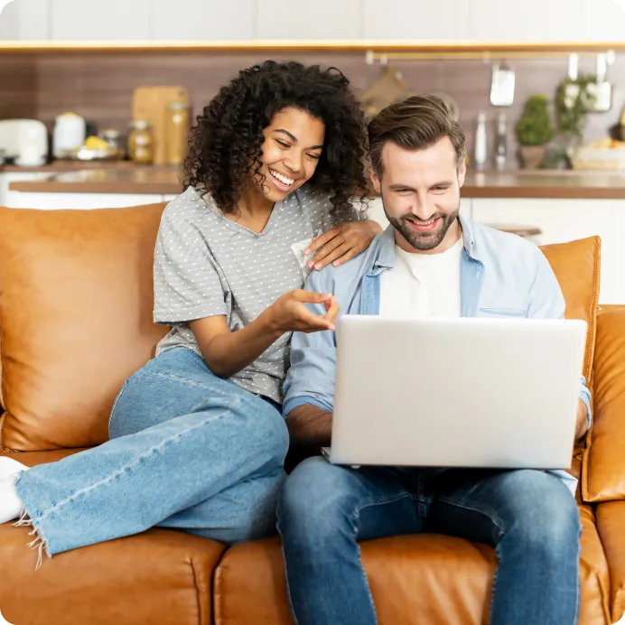 a couple looking at the laptop and smiling