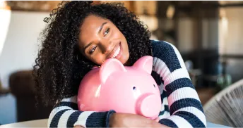 A woman hugging a pink piggy bank