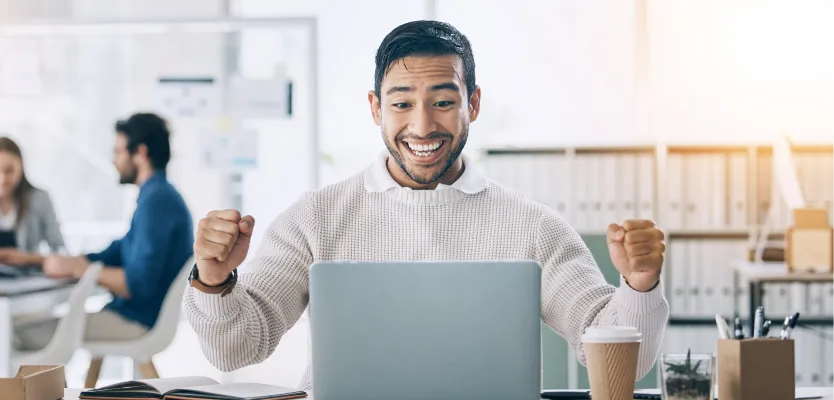 Man cheering with excitement in front of his laptop