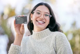 Woman smiling holding PenFed’s Visa debit card