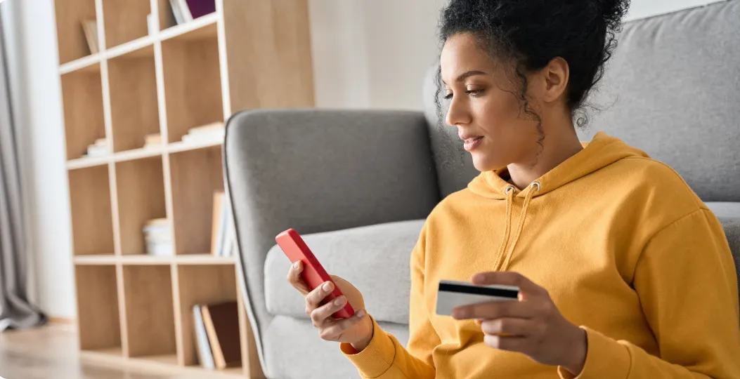 women viewing her mobile phone while holding a credit card