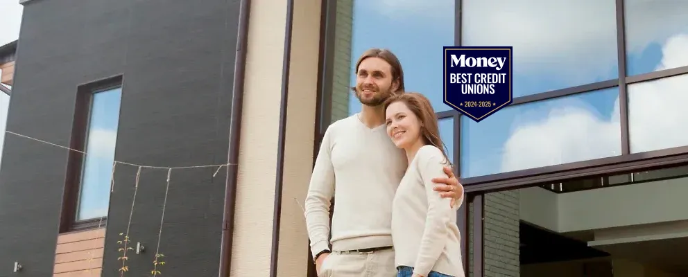 smiling couple standing in front of their home