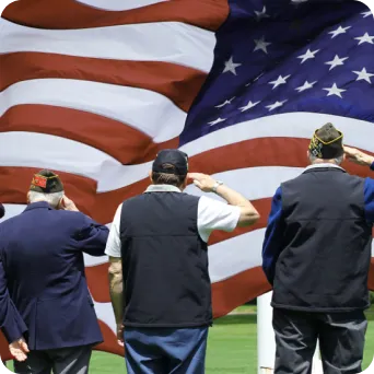 military service men saluting in front of an American Flag