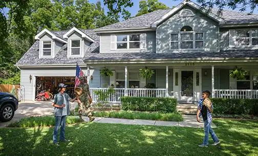 Air Force service member plays catch with sons after coming home from work in uniform.